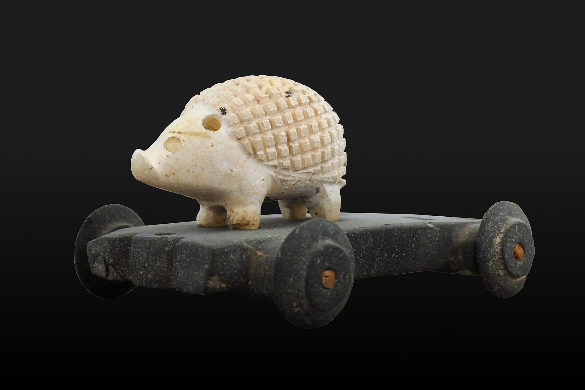 Imagem de referência de porco-espinho em carrinho, descrito nos dados abertos como um brinquedo de cerâmica na forma de um porco-espinho em cima de uma pequena plataforma com rodas