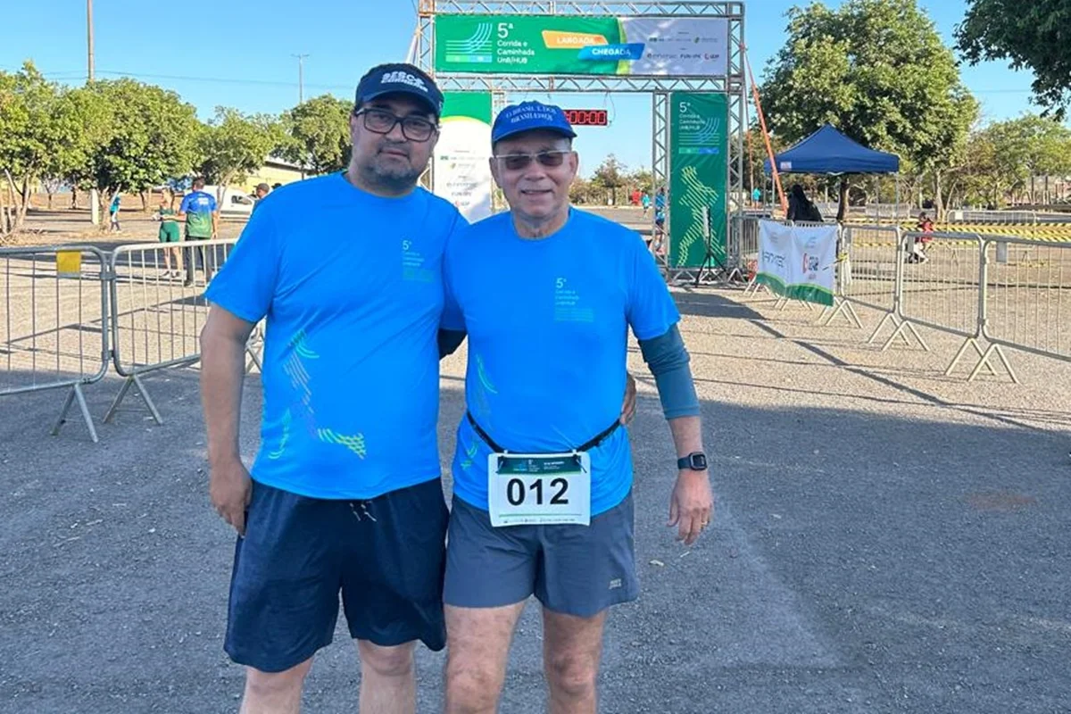 Foto colorida de dois homens se abraçando em frente a linha de chegada em uma chorrida de apoio a doação de órgãos - Metrópoles.