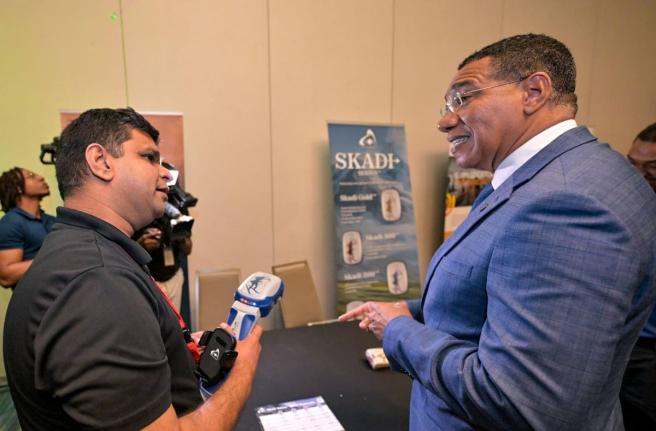 Prime Minister, Dr Andrew Holness (right), listens as Regional Sales Manager, EOS Positioning Systems, Satyam Dave (left), demonstrates one of the company’s devices during the Spatial ArcGIS User Conference at the AC Marriott Hotel in Kingston on Tuesday