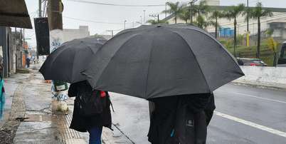 Pedestres se protegem da chuva na Avenida Interlagos, no Jardim Consórcio, zona sul de São Paulo, nesta sexta-feira, 2 de outubro de 2026 Foto: MARCO AMBROSIO/ATO PRESS/ESTADÃO CONTEÚDO