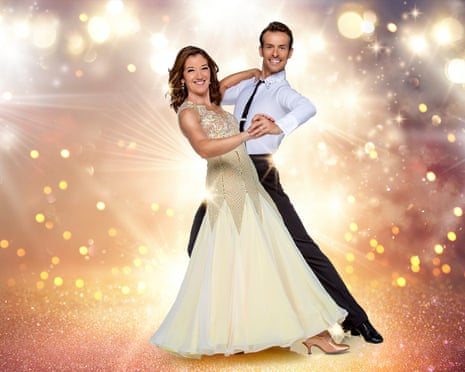 Publicity shot of a man and a woman ballroom dancing surrounded by stage lights