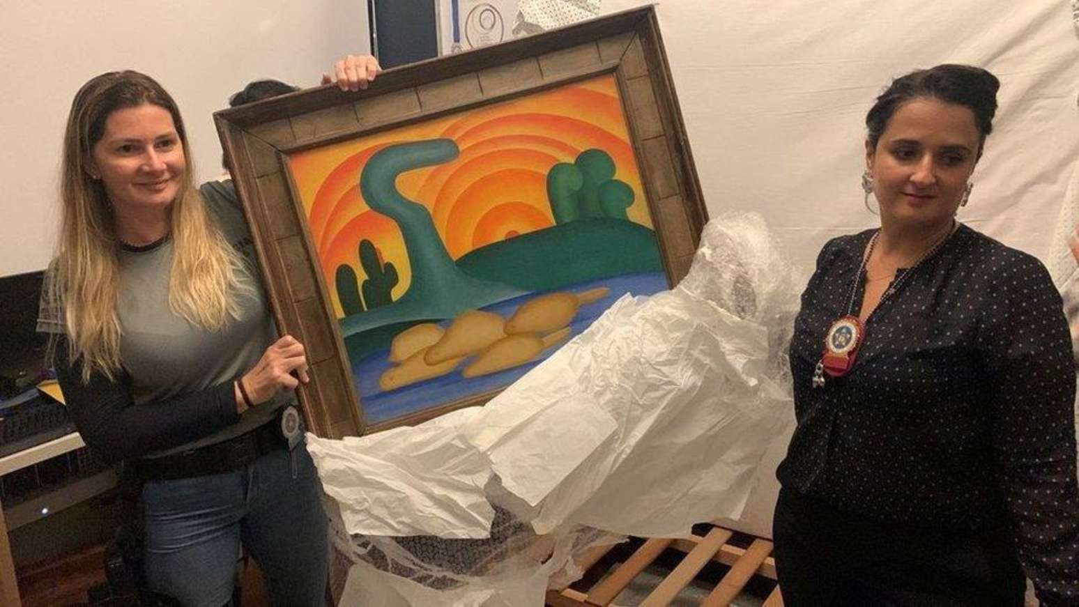 Policiais seguram o quadro O Sol Poente após recuperá-lo de furto em 2022, antes de a obra ser oferecida a Vorcaro